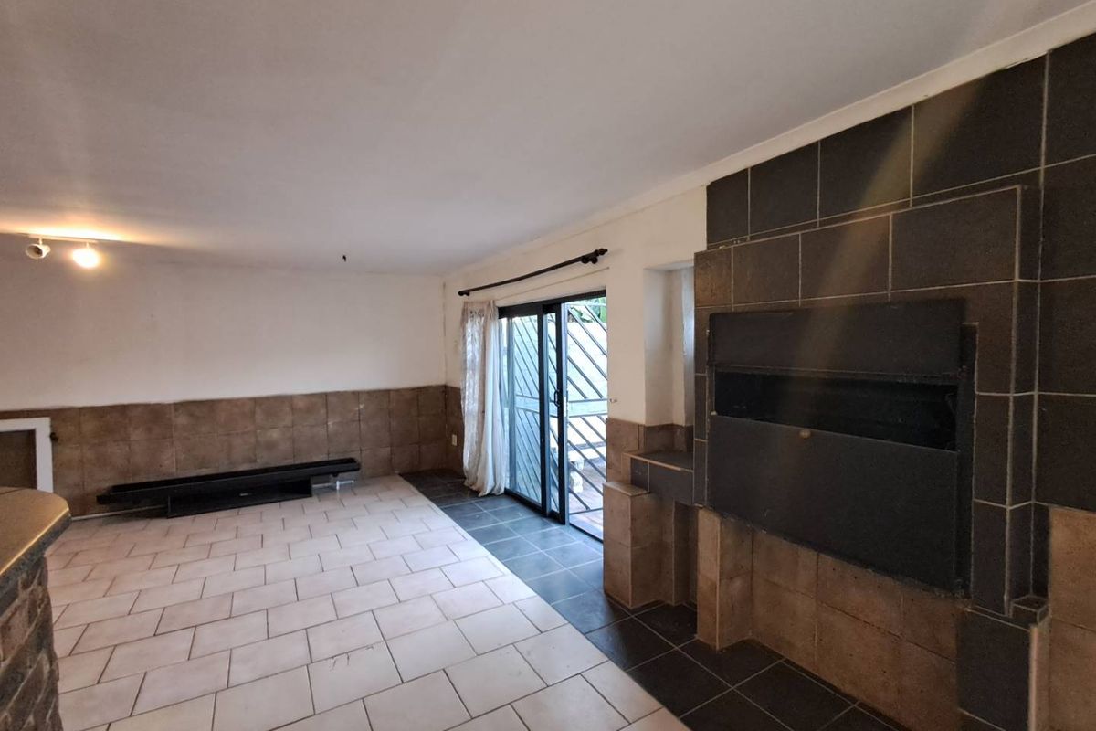 Spacious living area featuring a built-in fireplace with tiled surround, ceramic floor tiling, and sliding glass door access to the exterior.