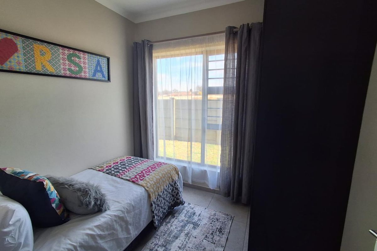 A well-lit bedroom featuring tiled flooring, security bars on the window, and neutral wall finishes.