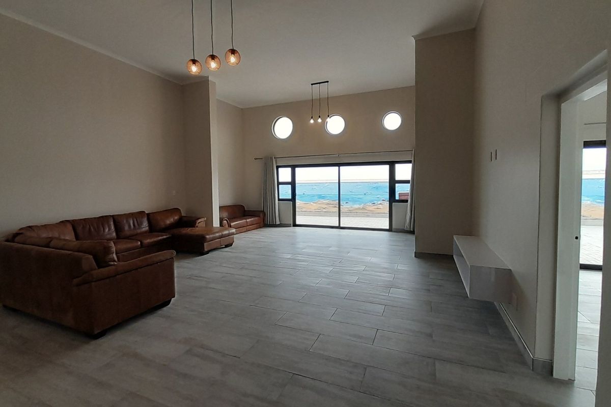 Spacious living area featuring large sliding glass doors with ocean views, modern tile flooring, and unique circular windows.