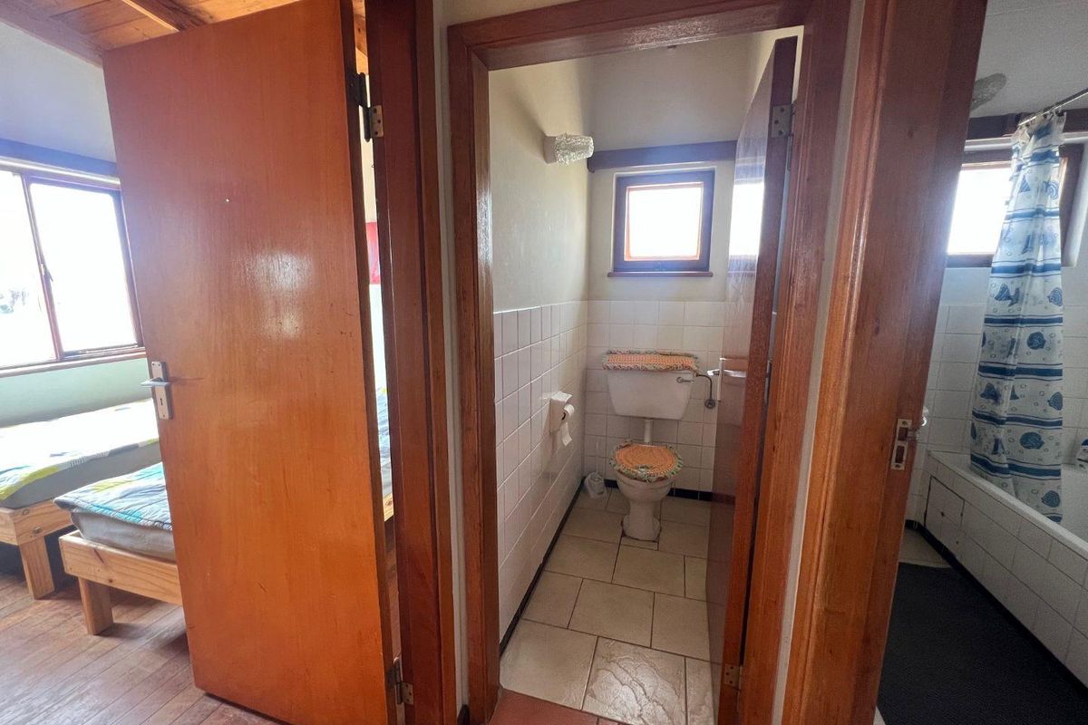 A view from a hallway looking into a bathroom featuring a toilet and tiled walls, with adjacent bedroom access.