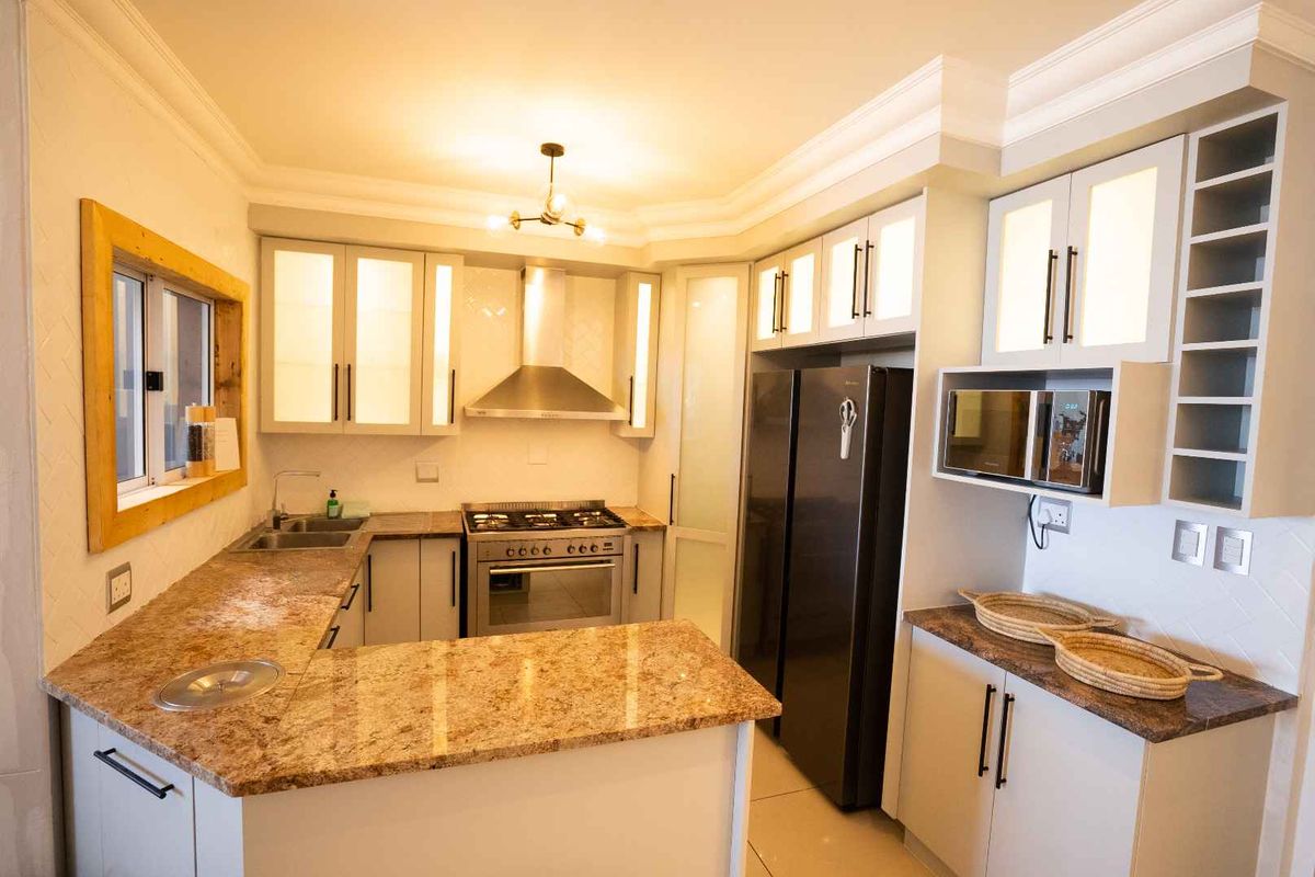 Modern kitchen featuring granite countertops, stainless steel gas stove, extractor fan, built-in microwave, and ample cabinetry with integrated wine storage.