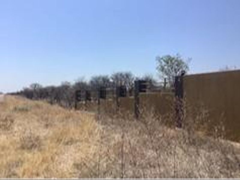 A view of the property perimeter featuring a solid boundary wall with integrated steel fence posts along the roadside.