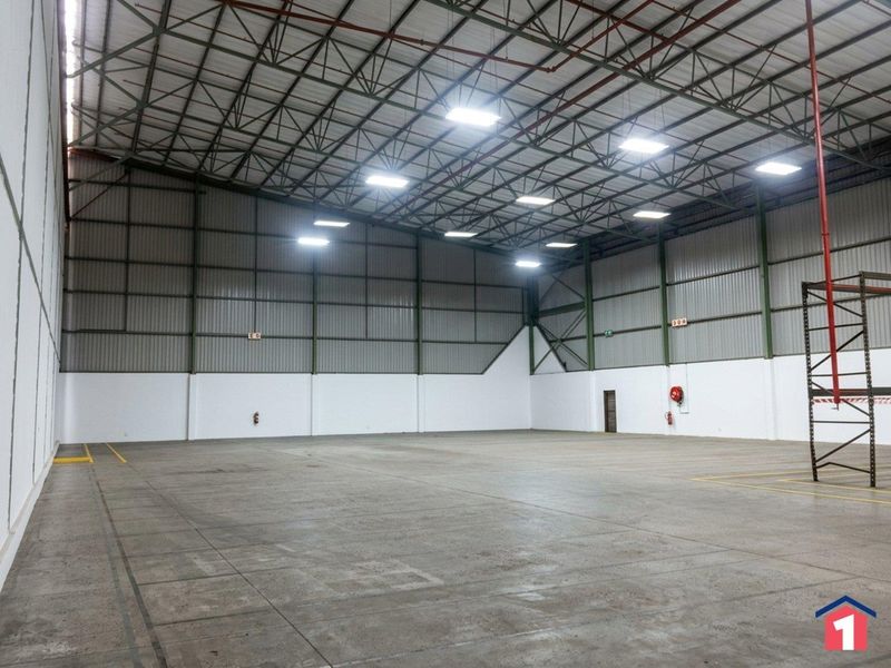 Spacious industrial warehouse unit featuring high-clearance exposed steel trusses, durable concrete flooring, and integrated industrial lighting, suitable for storage or manufacturing operations.
