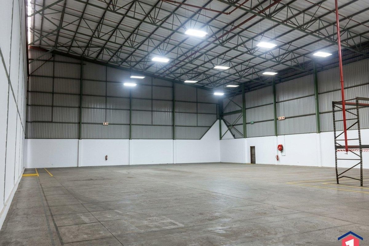 Spacious industrial warehouse unit featuring high-clearance exposed steel trusses, durable concrete flooring, and integrated industrial lighting, suitable for storage or manufacturing operations.