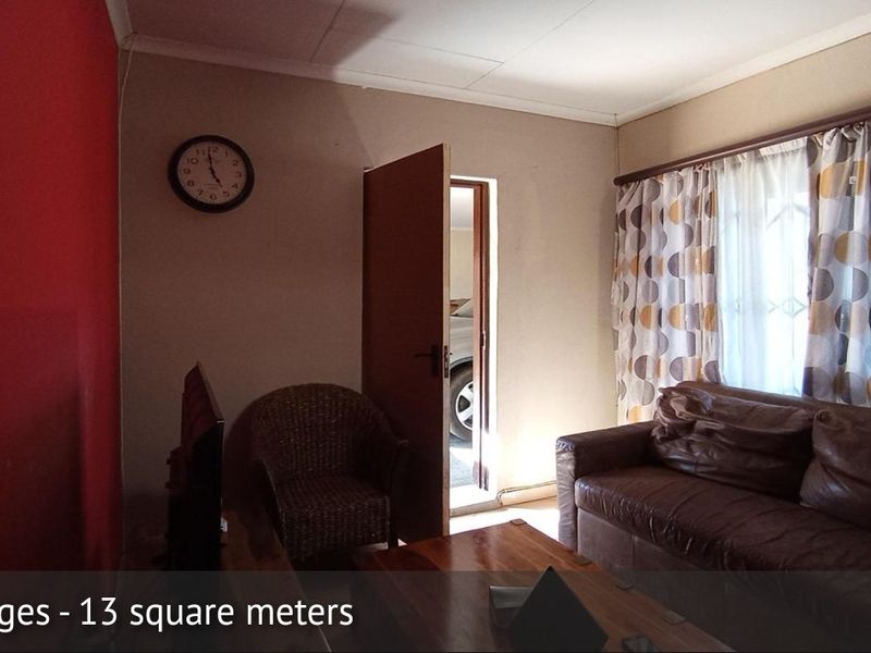A compact 13 square meter living room featuring neutral wall tones and a red accent wall.