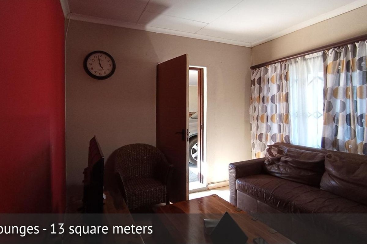 A compact 13 square meter living room featuring neutral wall tones and a red accent wall.