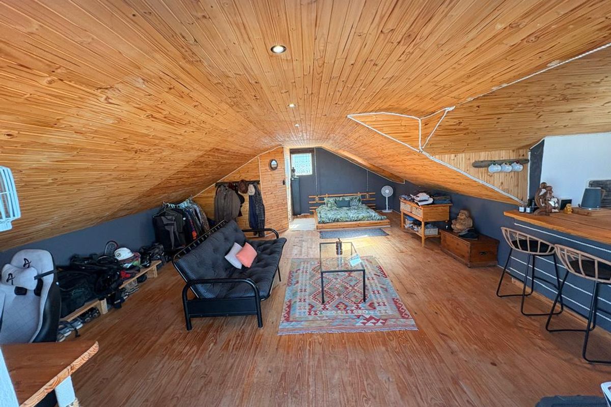 Spacious attic-style bedroom featuring a vaulted timber-clad ceiling, timber flooring, and a built-in breakfast bar area.