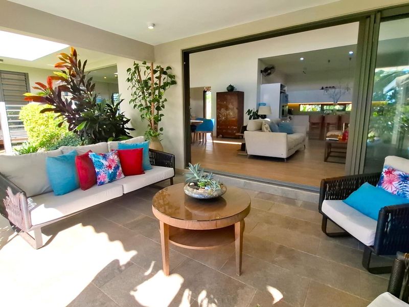 A spacious covered patio featuring large sliding glass doors that provide seamless indoor-outdoor flow to the open-plan living and kitchen area.