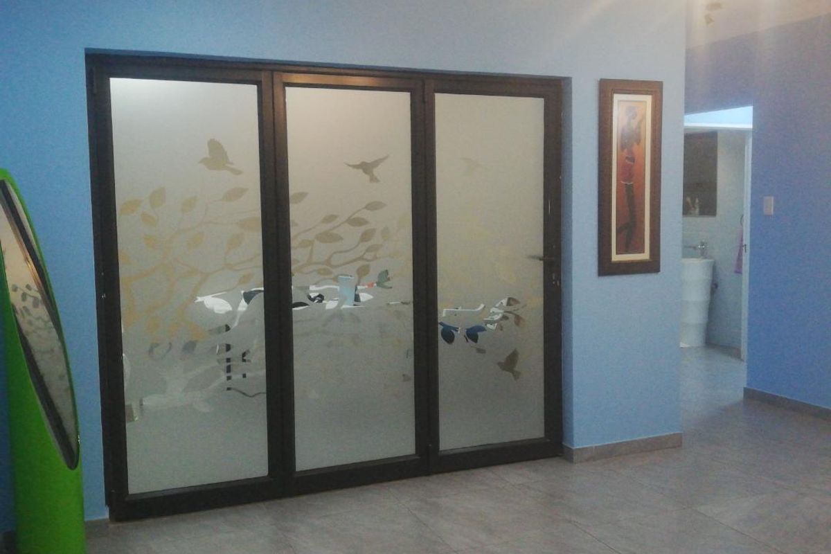 Interior view featuring a large three-panel frosted glass sliding door with decorative etching, leading to an adjacent room with tiled flooring.