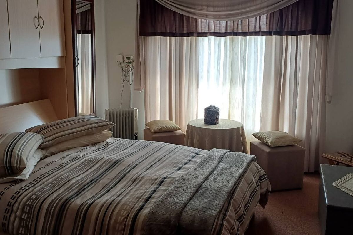 A cozy bedroom featuring built-in cabinetry and large windows with curtains, providing a functional and comfortable living space.