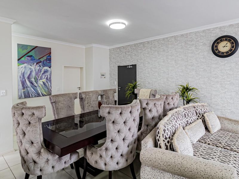 A well-maintained dining area featuring tiled flooring, textured feature wallpaper, and modern ceiling lighting, creating a comfortable and inviting space for meals.