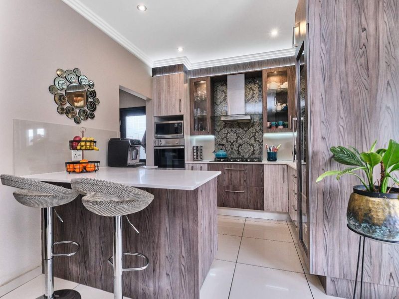 Modern kitchen featuring wood-grain cabinetry, stone countertops, integrated appliances, and a breakfast nook with recessed lighting.
