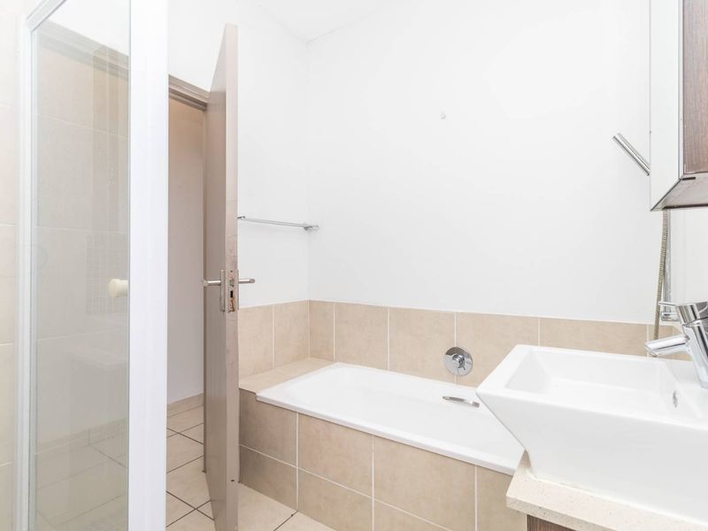 A functional bathroom featuring a built-in bathtub, separate shower enclosure, and a modern basin vanity with tiled splashbacks.