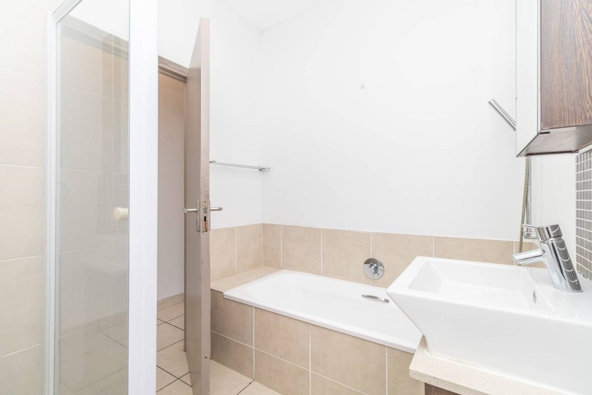 A functional bathroom featuring a built-in bathtub, separate shower enclosure, and a modern basin vanity with tiled splashbacks.