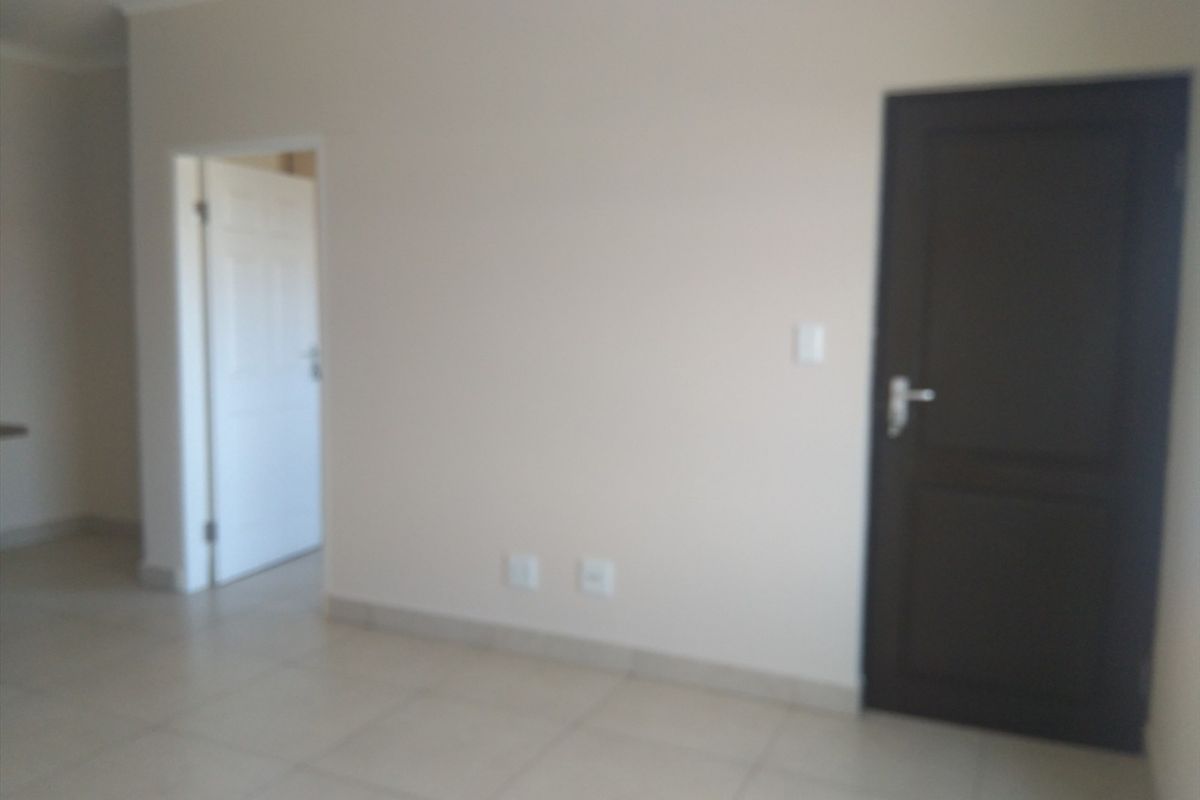 An empty interior space featuring tiled flooring, neutral wall paint, and two internal doors leading to adjacent rooms.