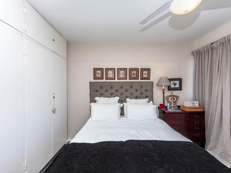 A well-maintained bedroom featuring a built-in wardrobe and a ceiling fan, offering a functional and comfortable living space.