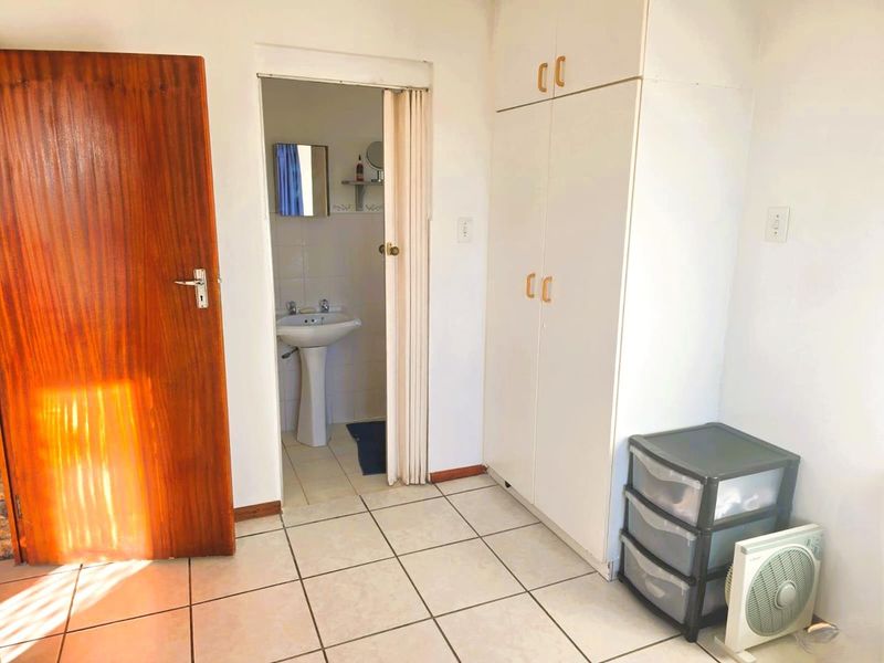Bedroom featuring tiled flooring, a built-in wardrobe, and an en-suite bathroom with a pedestal basin.