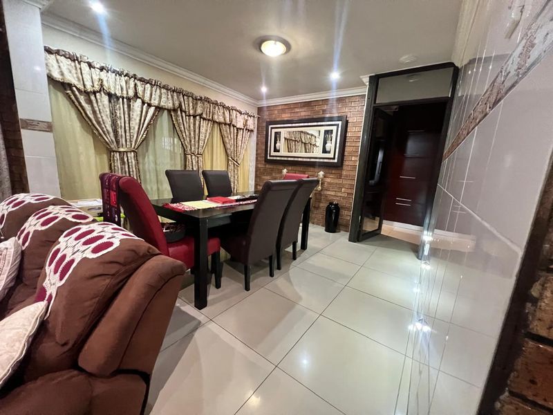 Dining area featuring an exposed brick feature wall, ceramic floor tiles, and recessed lighting, providing a functional space for family meals.
