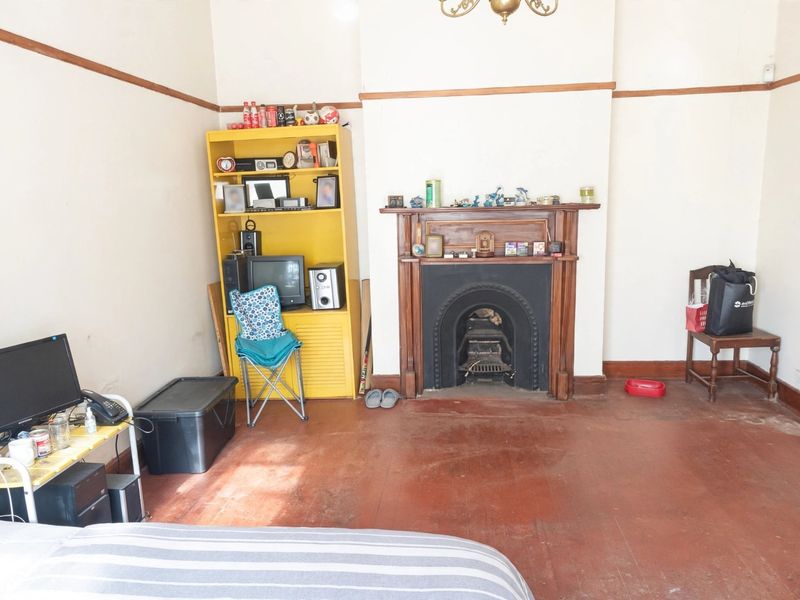 Living room featuring a traditional cast iron fireplace with a timber mantel, picture rails, and original timber flooring.