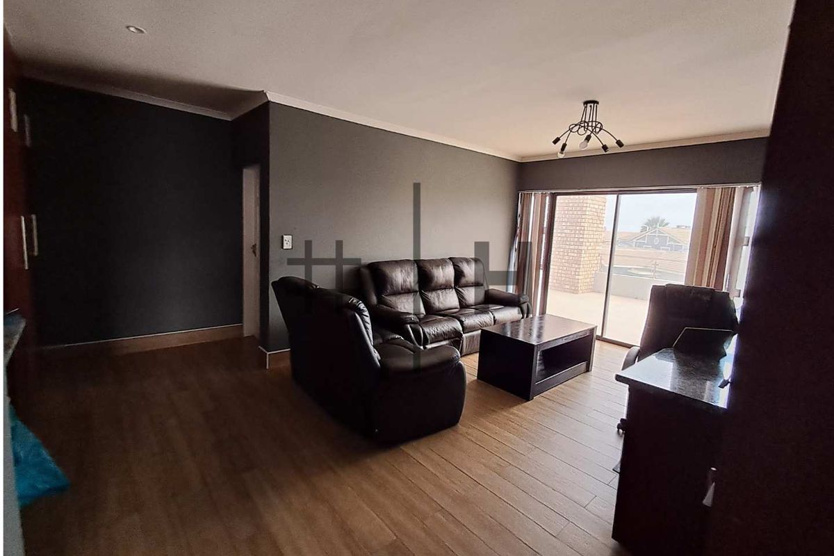 Spacious living room featuring wood-look flooring, dark accent walls, and large sliding glass doors providing access to an outdoor area.