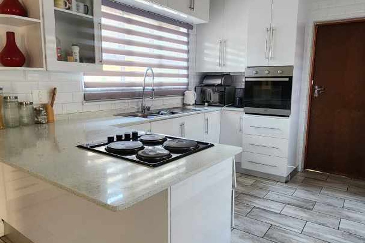 Modern kitchen featuring white cabinetry, stone countertops, built-in oven, gas hob, and tiled flooring.