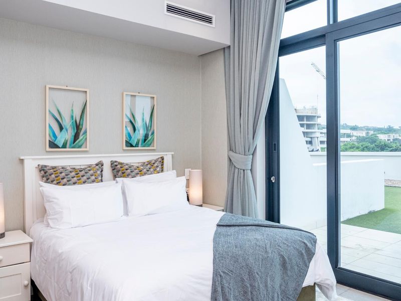 Modern bedroom featuring ducted air conditioning and a large sliding glass door providing direct access to a private balcony.