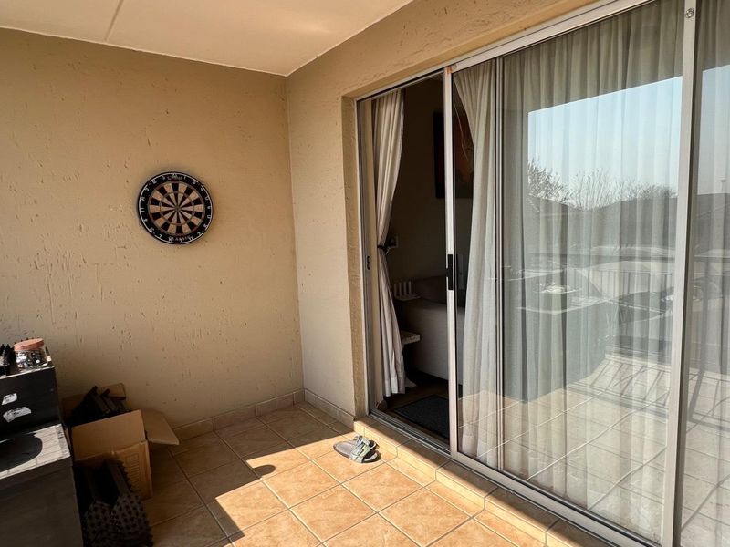 A covered balcony area featuring tiled flooring and a large sliding glass door providing access to the interior living space.