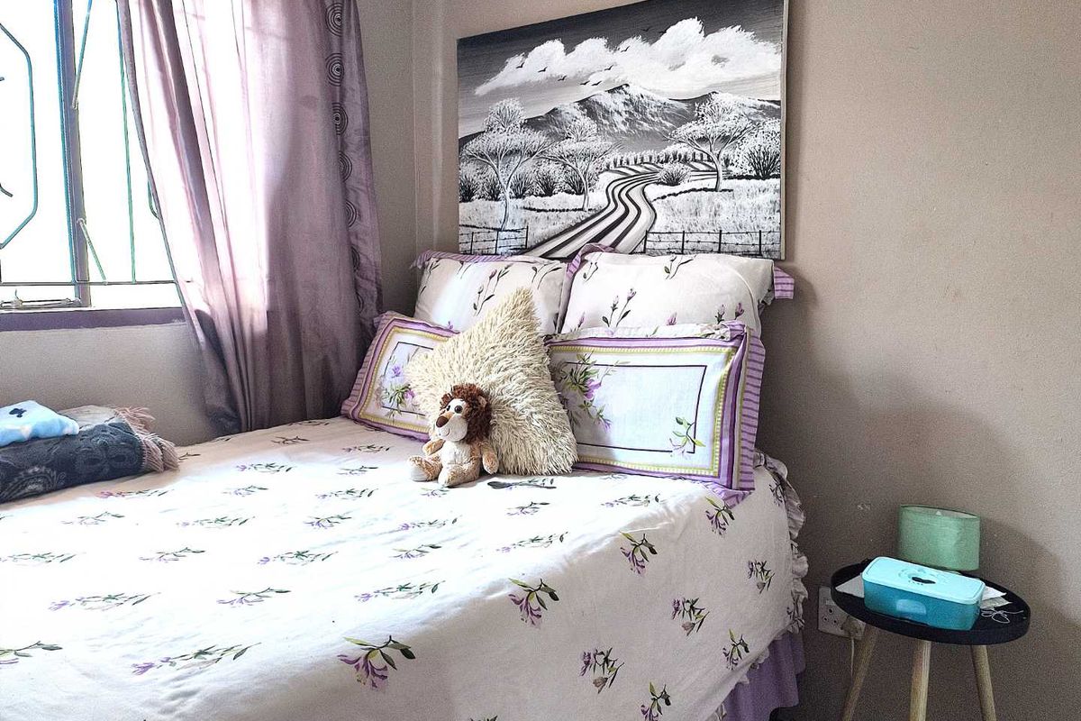 A cozy bedroom featuring a window with security bars and neutral wall finishes.