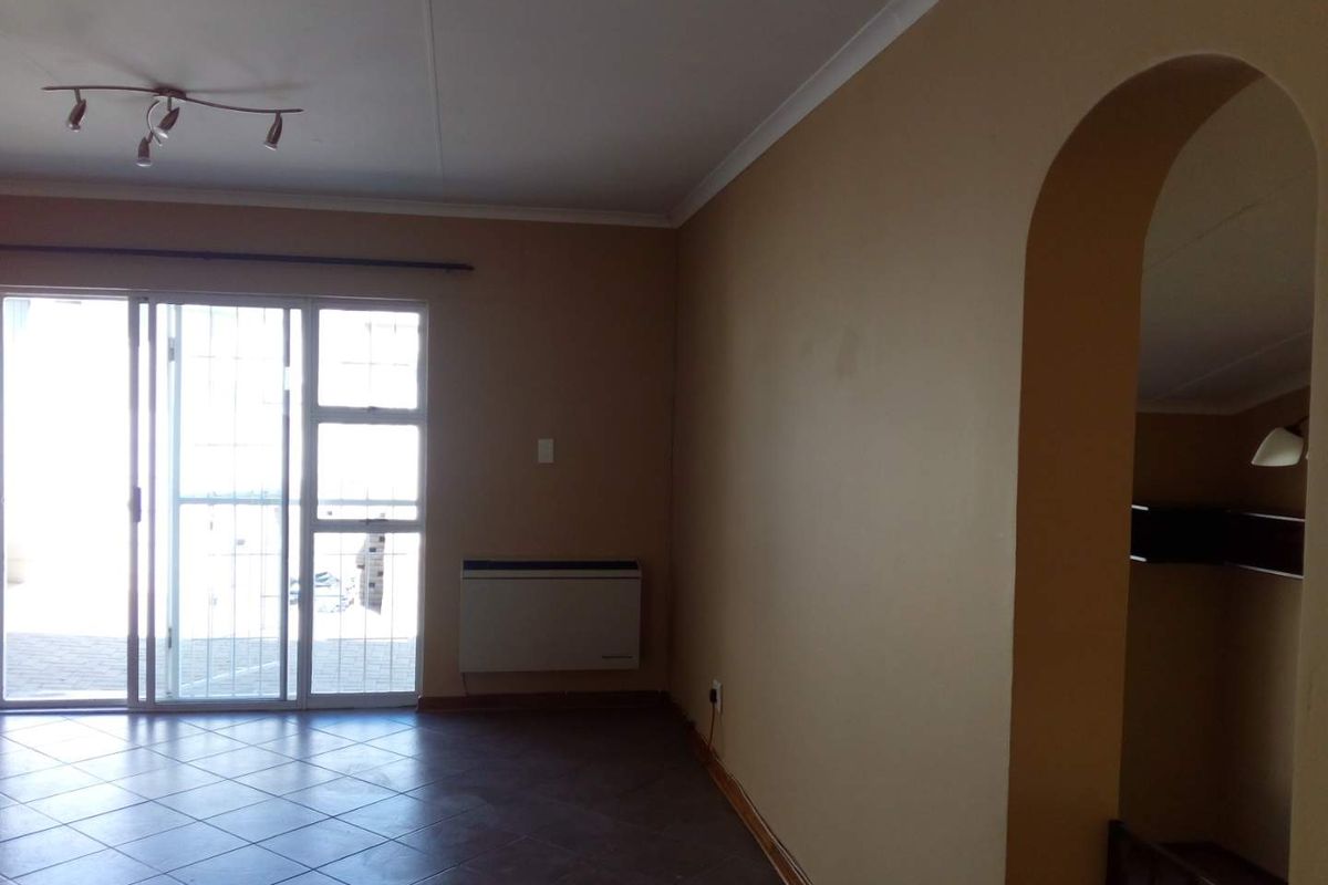 Spacious living area featuring tiled flooring, a wall-mounted heater, and a sliding glass door providing access to the exterior.