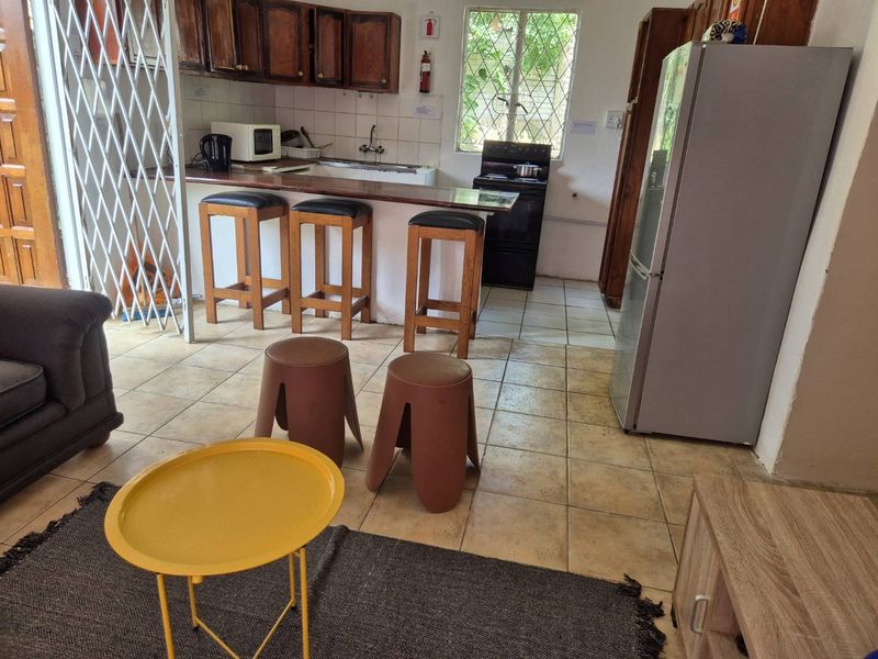 Open plan living and kitchen area featuring wooden cabinetry, tiled flooring, and a functional kitchen layout with a freestanding stove.