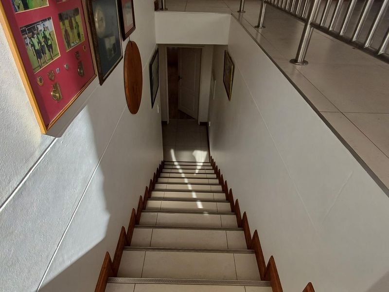 A tiled staircase featuring a modern stainless steel balustrade, leading down to a lower level hallway.