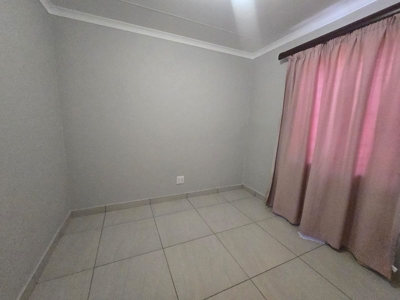 A clean, empty bedroom featuring neutral tiled flooring, light grey walls, and classic cove cornicing, ready for personalization.