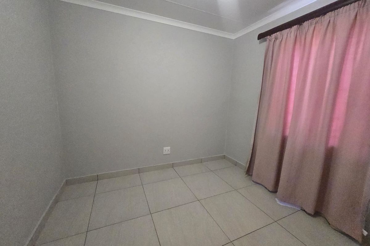 A clean, empty bedroom featuring neutral tiled flooring, light grey walls, and classic cove cornicing, ready for personalization.