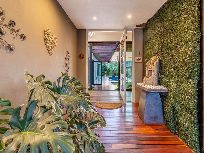 Inviting entrance hall featuring warm timber flooring and a striking vertical garden wall, leading directly out to the pool area.