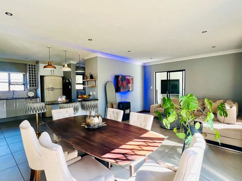 Spacious open-plan living area featuring a modern kitchen with island, dining space, and seamless flow to the outdoor area through sliding glass doors.