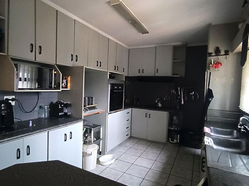 A functional kitchen featuring extensive built-in cabinetry, a built-in oven, double sink, and tiled flooring, offering a practical layout with potential for modern updates.