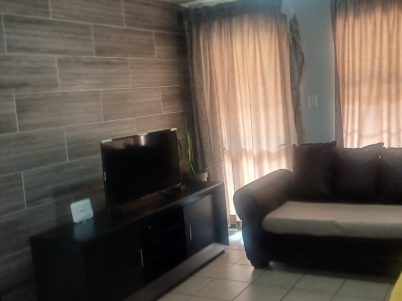 Living room featuring a wood-look tiled accent wall, ceramic floor tiles, and access to an outdoor area through a sliding glass door.