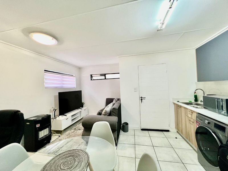 Open plan living area featuring a compact kitchen with light wood cabinetry, tiled floors, and a combined lounge space.