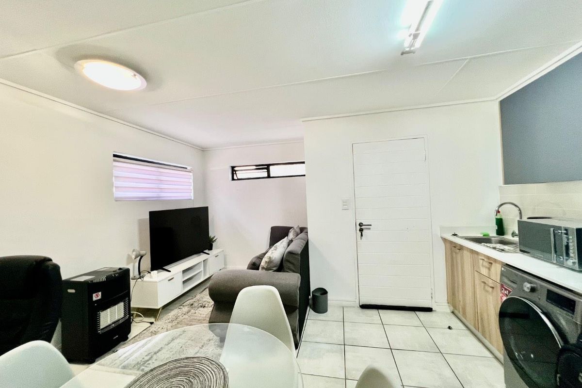 Open plan living area featuring a compact kitchen with light wood cabinetry, tiled floors, and a combined lounge space.