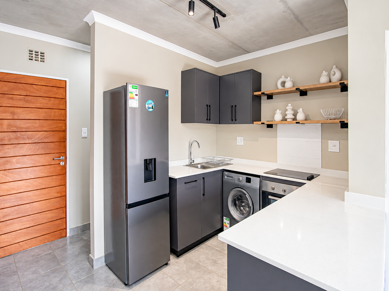 Modern kitchen featuring dark grey cabinetry, white quartz countertops, integrated appliances, open shelving, and a stylish exposed concrete ceiling.