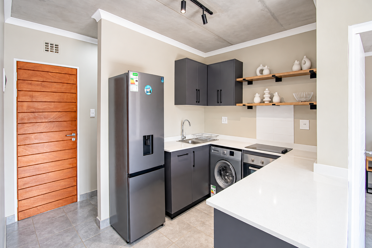 Modern kitchen featuring dark grey cabinetry, white quartz countertops, integrated appliances, open shelving, and a stylish exposed concrete ceiling.
