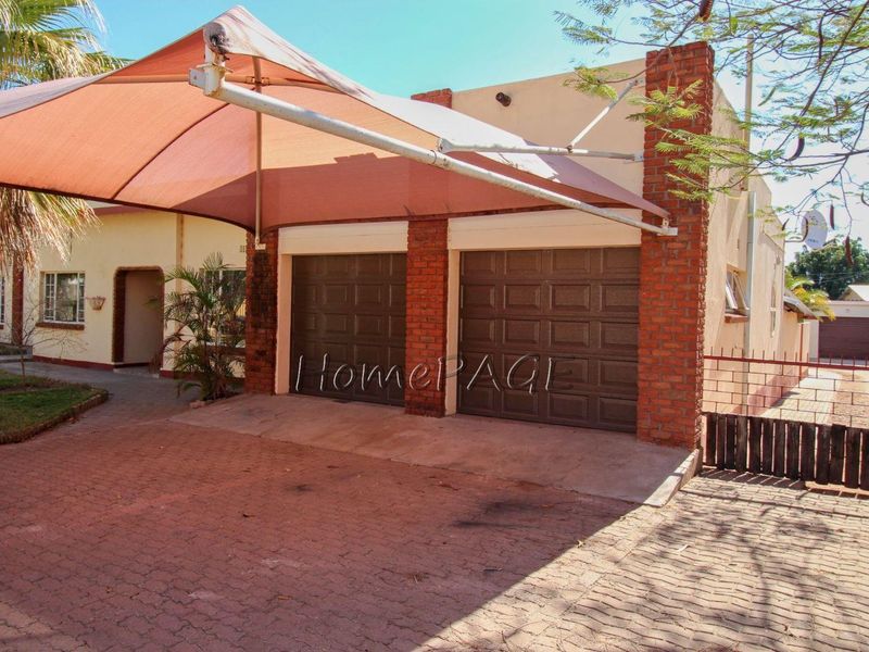 Front exterior view featuring a double garage with a shade sail covering the paved driveway area.