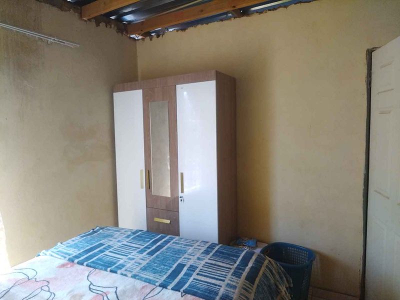 A bedroom featuring exposed timber roof beams and unfinished wall surfaces, requiring cosmetic attention and ceiling completion.