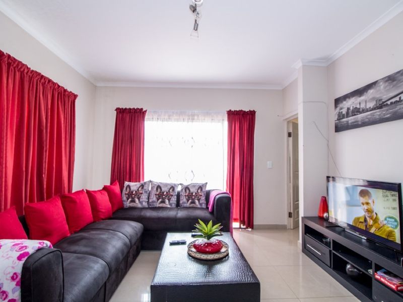 A comfortable living room featuring neutral tiled flooring and classic cove cornicing, providing a functional and well-maintained space for relaxation.