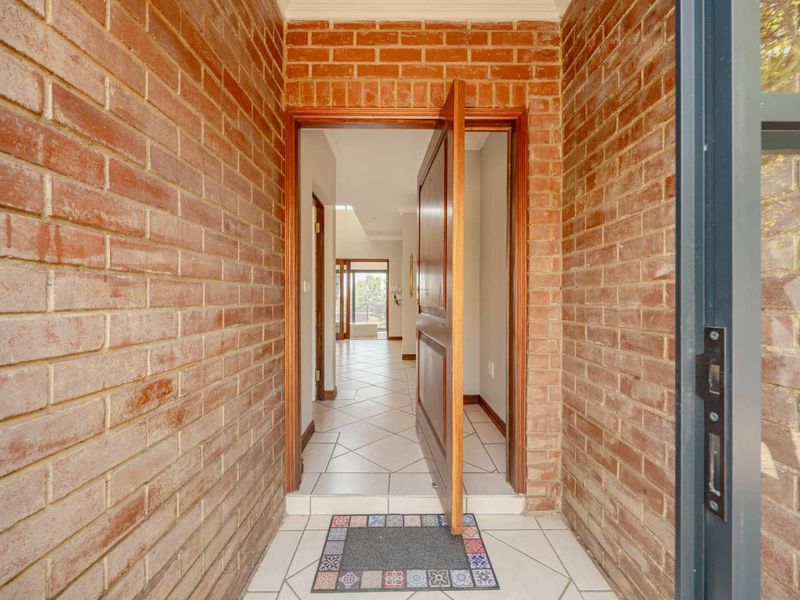 A welcoming entrance hall featuring exposed brick walls and tiled flooring, leading into the main living area of the home.