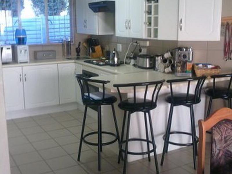 A functional kitchen featuring white cabinetry, laminate countertops, a breakfast bar, and tiled flooring, providing a practical layout for daily meal preparation.