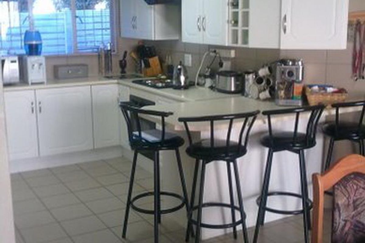 A functional kitchen featuring white cabinetry, laminate countertops, a breakfast bar, and tiled flooring, providing a practical layout for daily meal preparation.