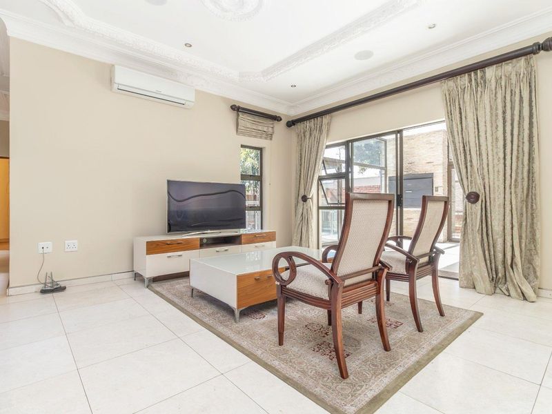 A bright living room featuring tiled floors, decorative ceiling cornices, recessed lighting, and sliding glass doors providing access to the outdoor area.