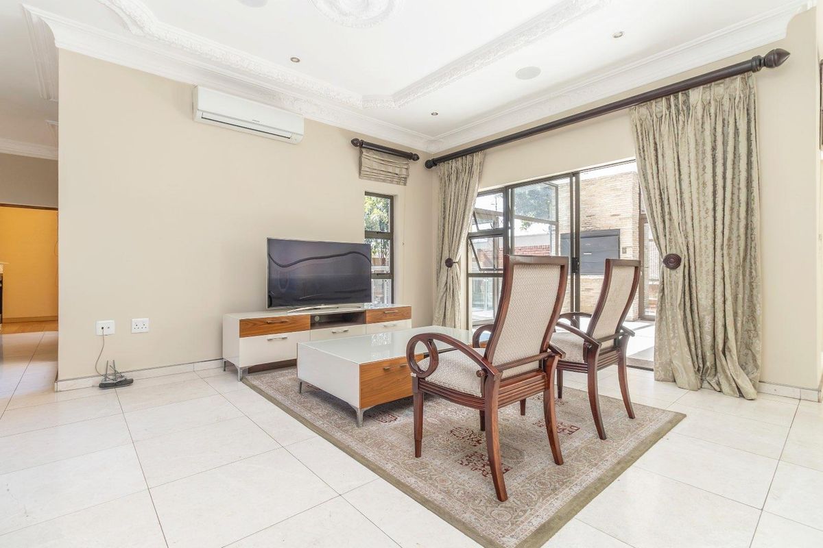 A bright living room featuring tiled floors, decorative ceiling cornices, recessed lighting, and sliding glass doors providing access to the outdoor area.