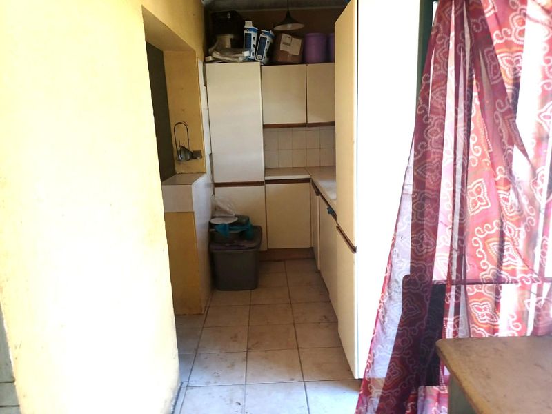 A compact scullery or utility area featuring built-in cabinetry and tiled flooring, providing functional storage and prep space.